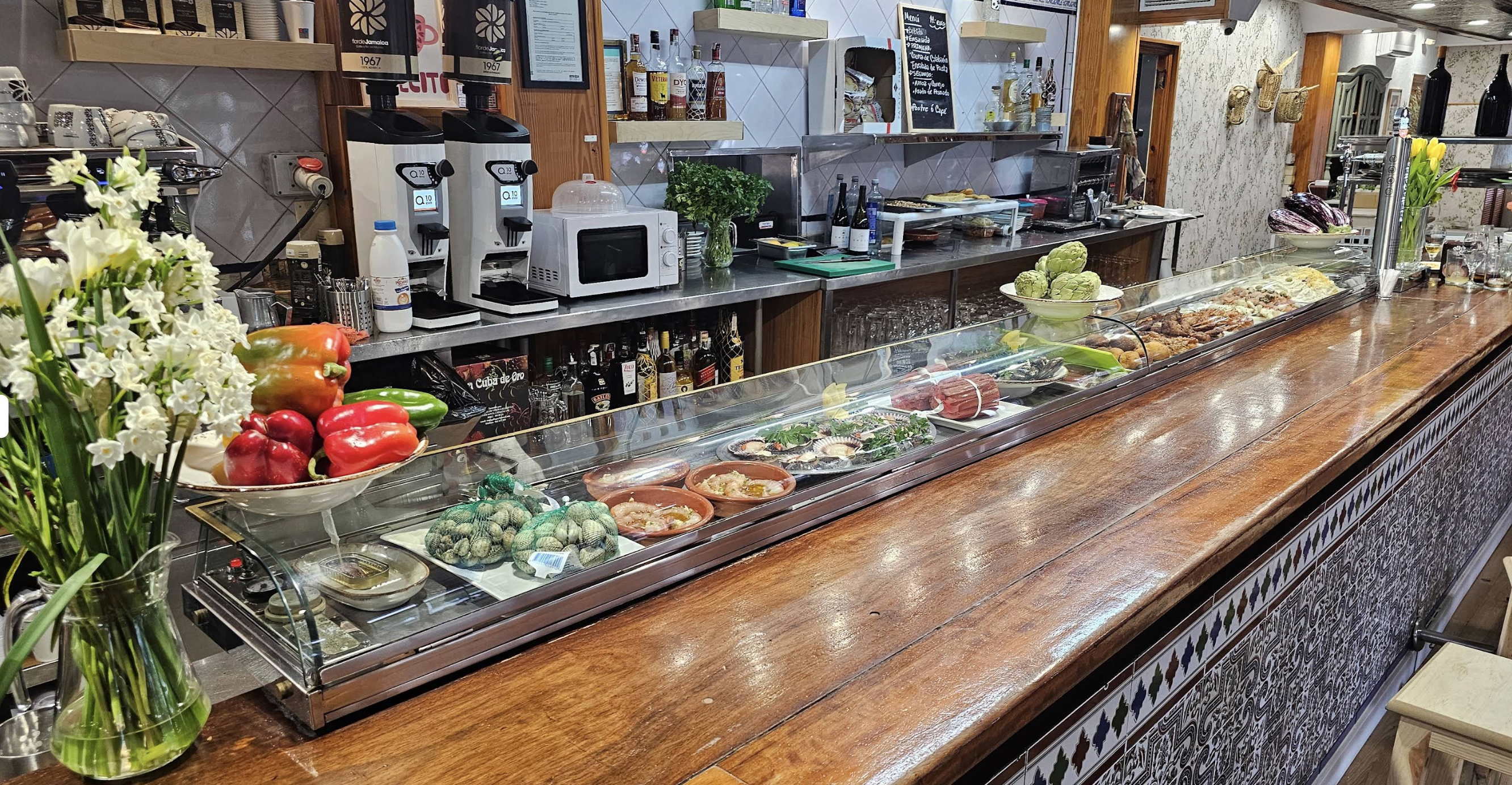 Vitrina de tapas y barra del Restaurante El Olivo con flores frescas